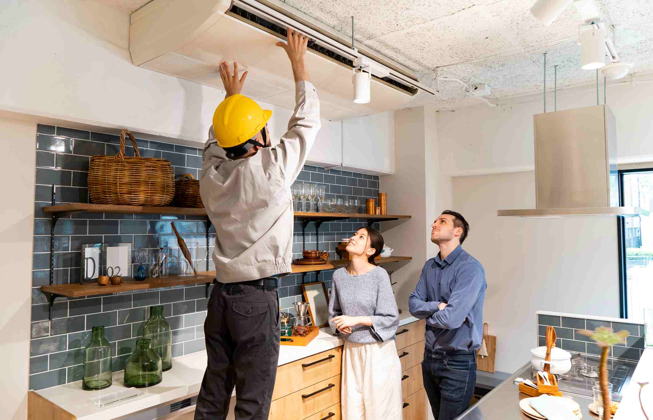 A repairman wearing a BROCK - yellow helmet and checking the AC air conditioner