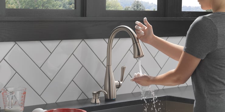 person touching a faucet with the back of their hand