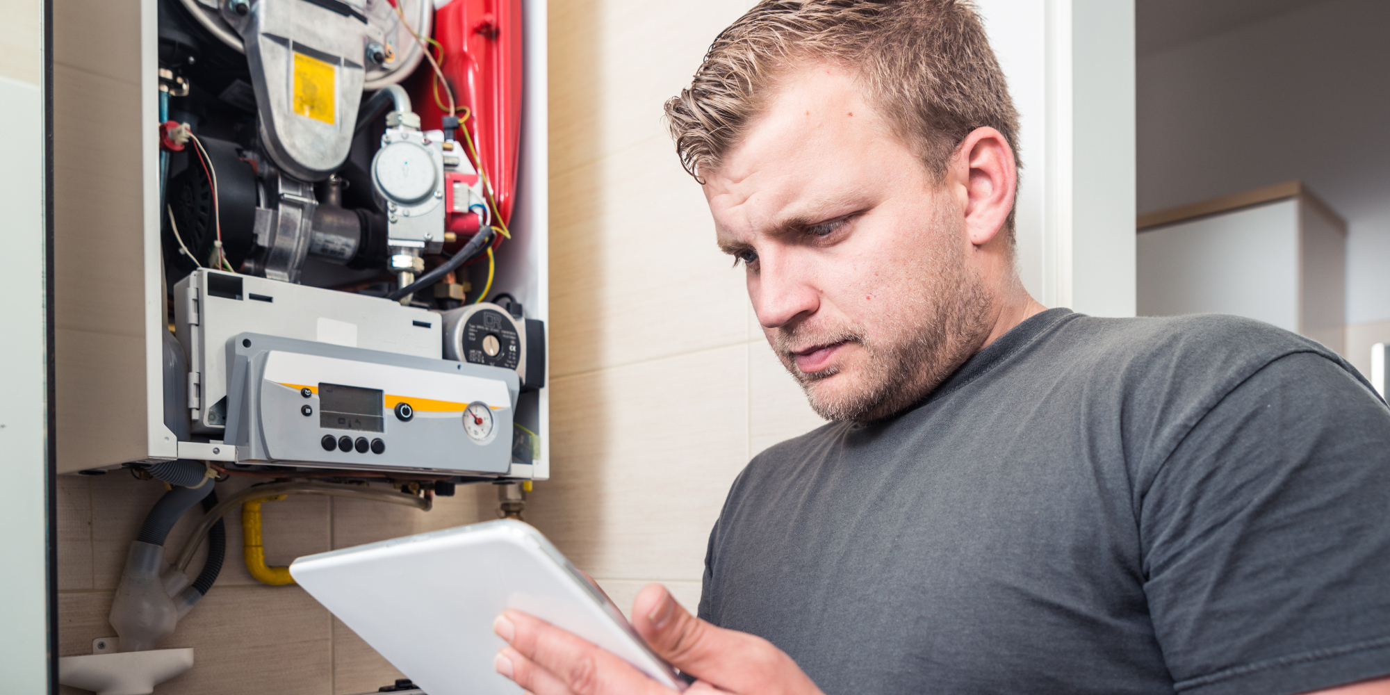 Worker checking iPad while repairing a boiler