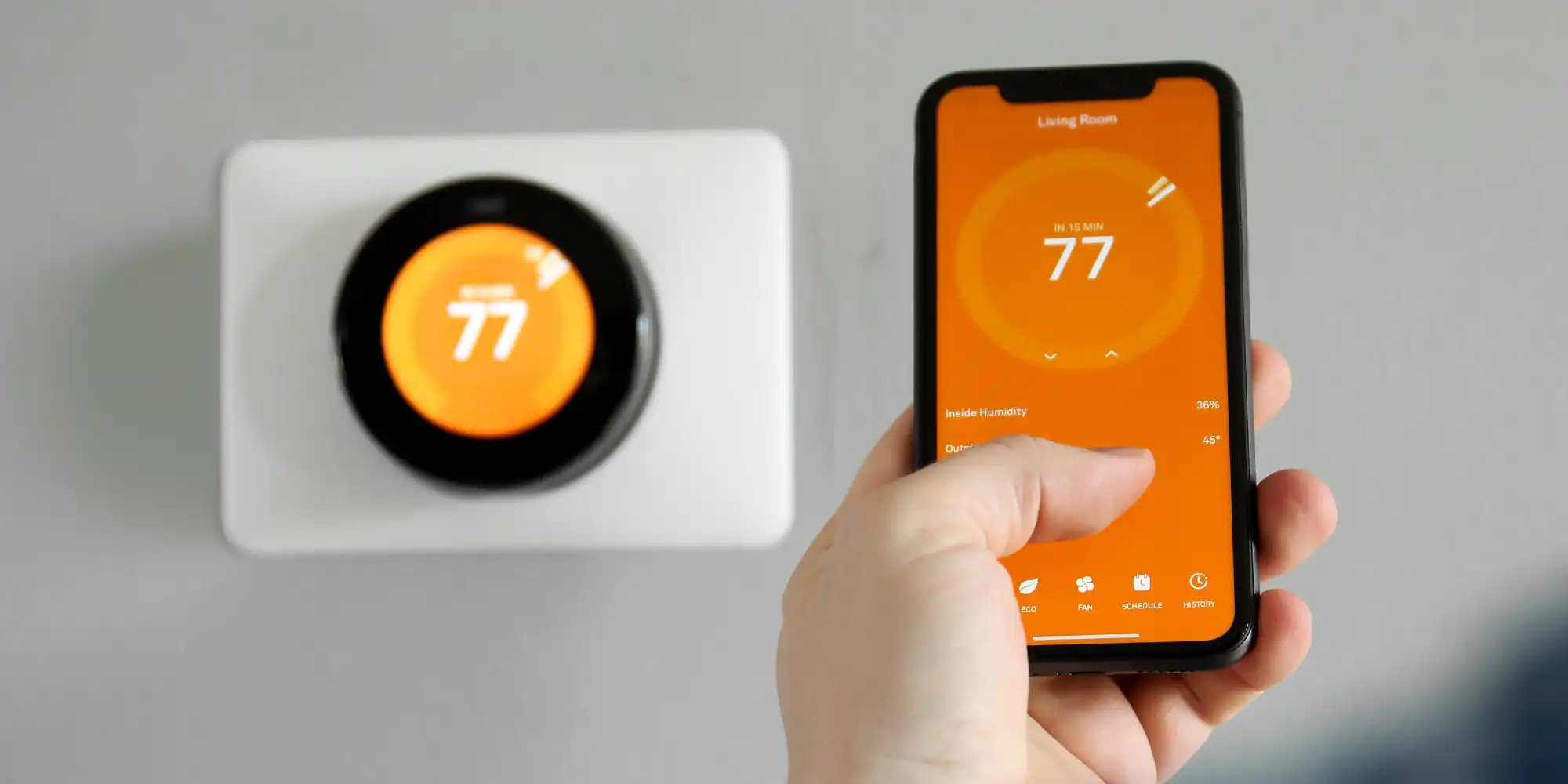 hand holding a phone controlling their smart thermostat temperature. 