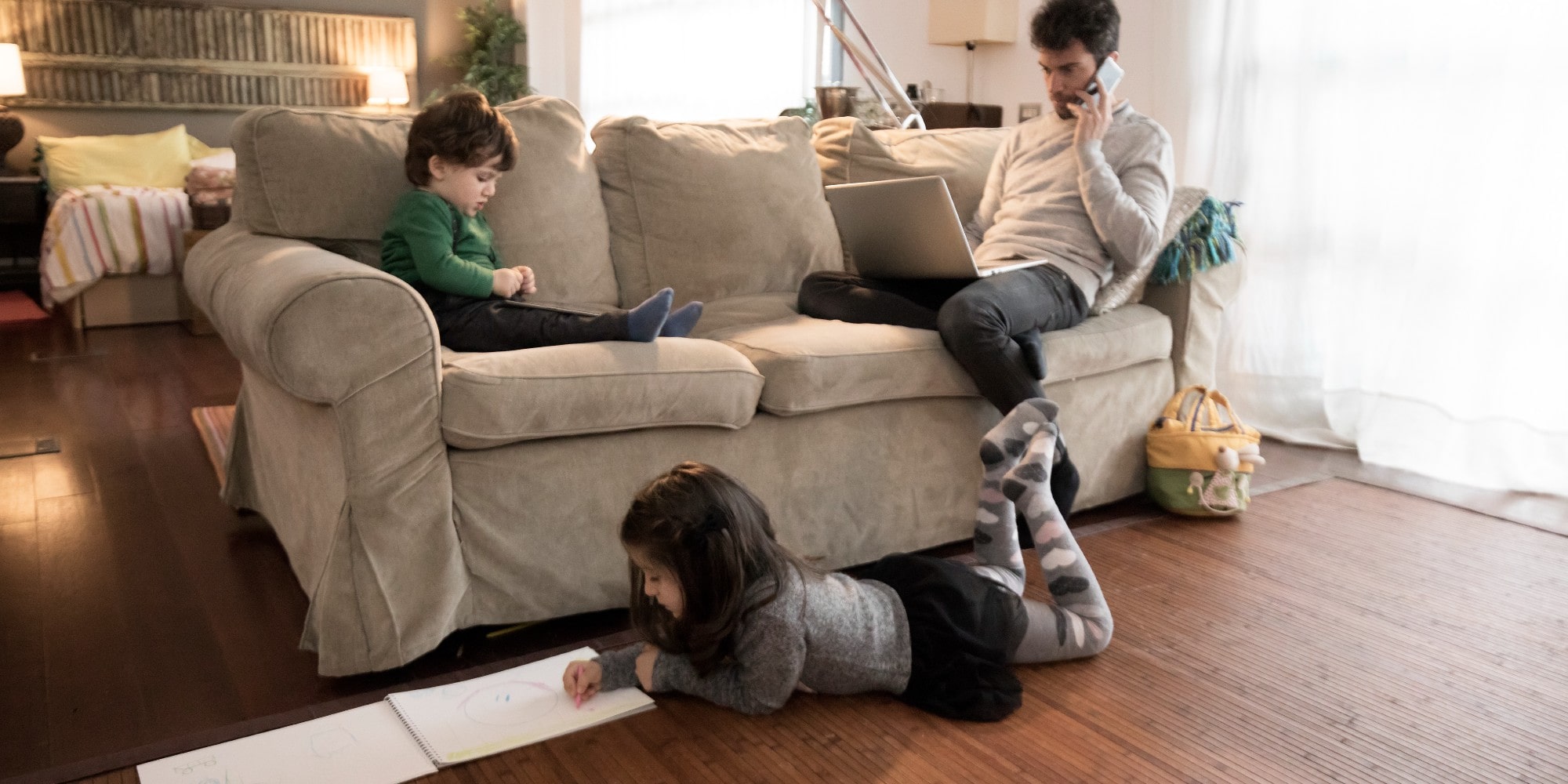 male father and two children sitting in in a living room working