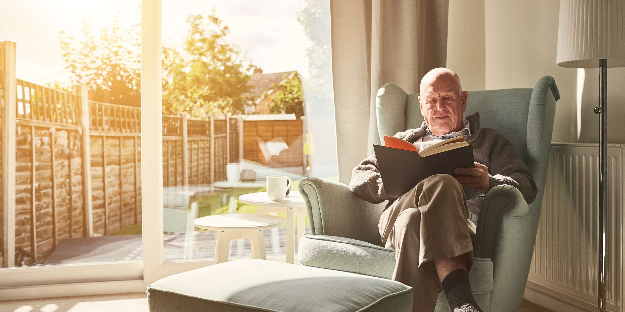 man sitting on arm chair and reading a book