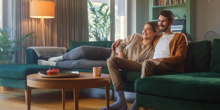 Couple watches TV together while sitting on a couch in the living room.