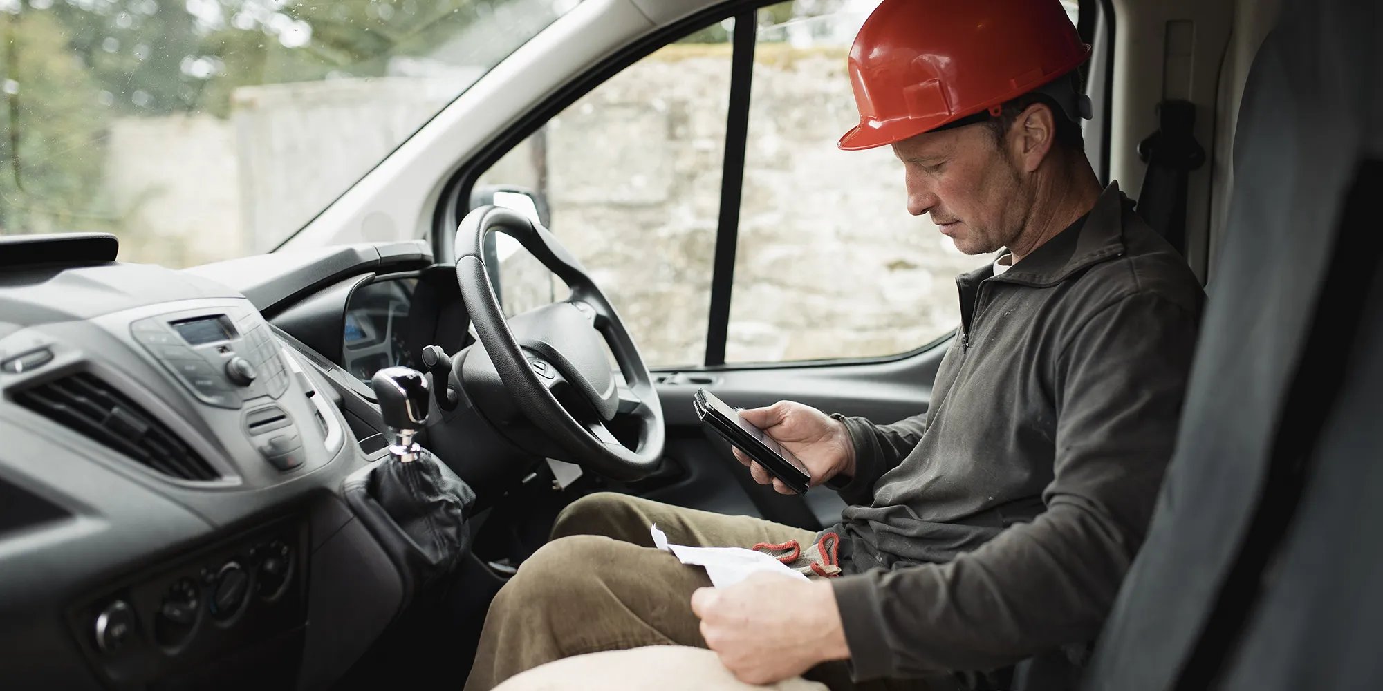 Contractor checking cellphone in a work van