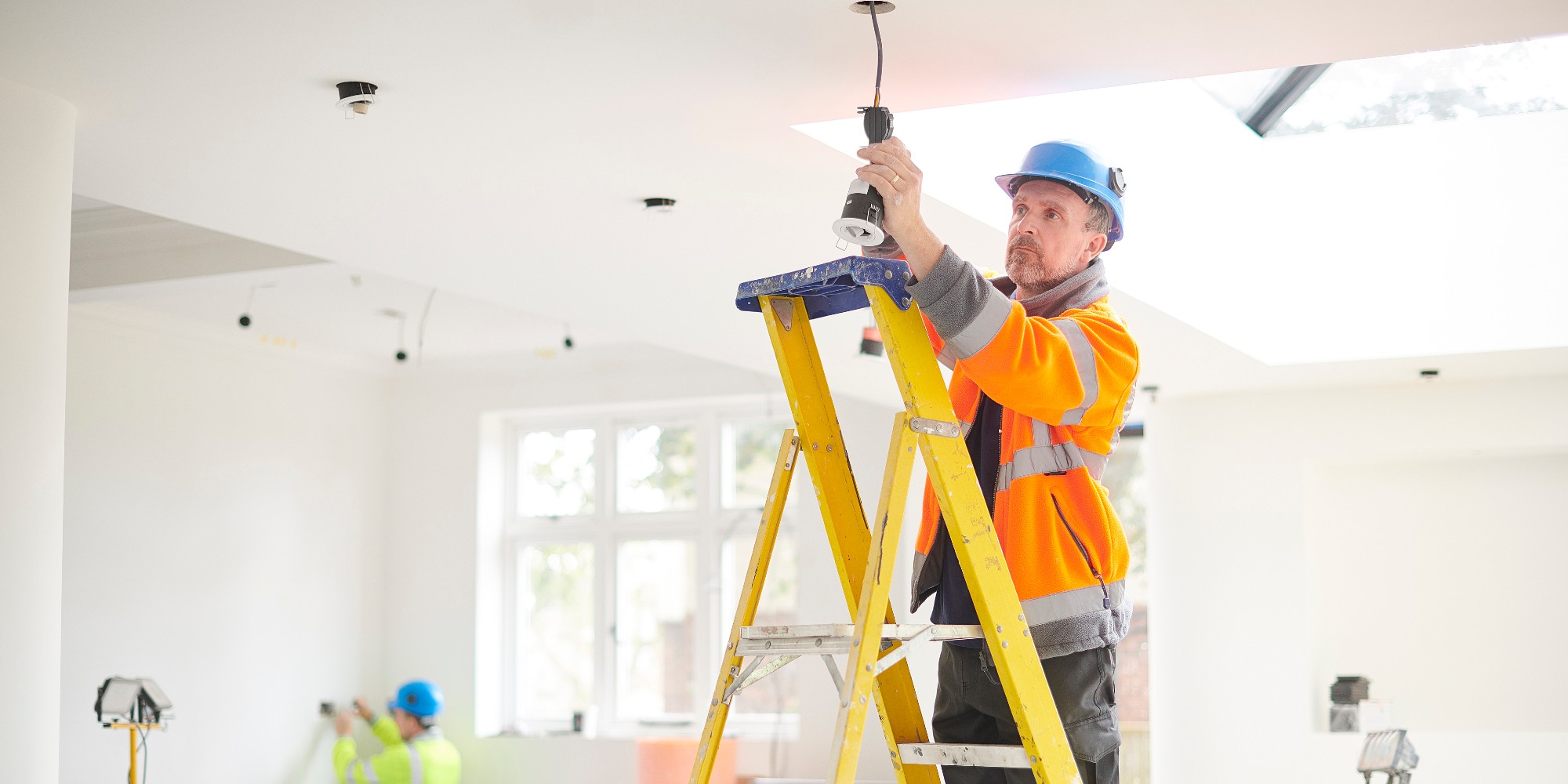 Electrician Installing Pot Light In Residential Home Standing On Ladder